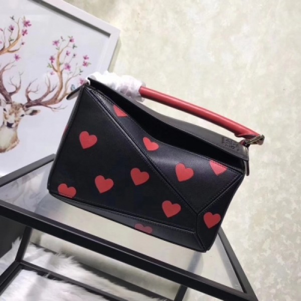 羅意威Loewe Puzzle Hearts Bag 心愛限量系列出貨 其採用先進的皮革鑲嵌細工工藝 以紅色愛心圖案為標誌性設計搭配黑色小牛皮 俏皮活潑的心型圖案 帶來細膩動人的青春韻味 更是愛不釋手 沒有哪個女生能逃過